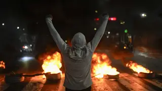 A protestor raises his arms in front of tires on fire in Caracas, Venezuela, the day after the presidential election