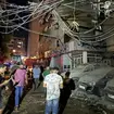 People gather near a destroyed building that was hit by an Israeli airstrike in the southern suburbs of Beirut, Lebanon