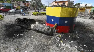 A destroyed statue of the late Venezuelan president Hugo Chavez lies next to its base in Valencia, Venezuela