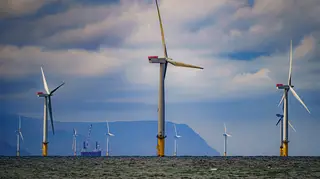 Offshore wind turbines in the sea with hills in the distance