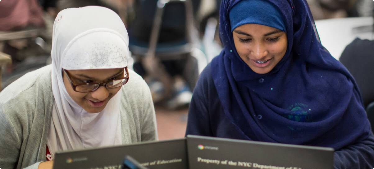 Twee studente met hijabs wat op Chromebooks werk