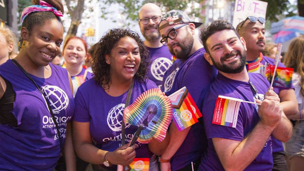 Un grupo de empleados de Google viste camisetas moradas y lleva banderas del arco iris en un desfile