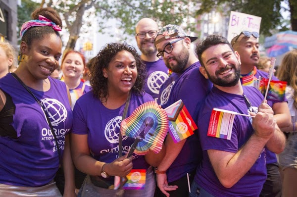 Un grupo de empleados de Google viste camisetas moradas y lleva banderas del arco iris en un desfile