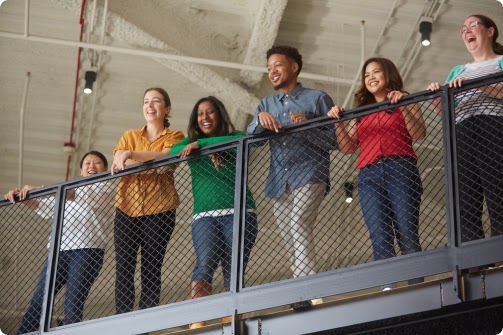 A group of 6 Googlers from different backgrounds, overlooking an office balcony.