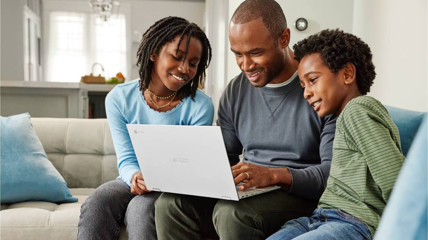 Homem trabalhando em um Chromebook em casa com duas crianças olhando para a tela juntas.