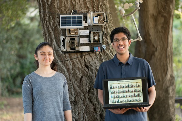 Os alunos Aditya Shah e Sanjana Shah posando em frente ao dispositivo Smart Wildfire Sensor desenvolvido com tecnologia de IA.