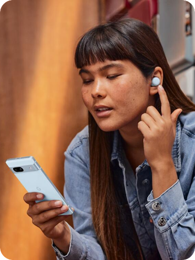 Um utilizador do Android está a manter uma conversa tocando no auricular com o dedo enquanto olha para o seu telemóvel Android.