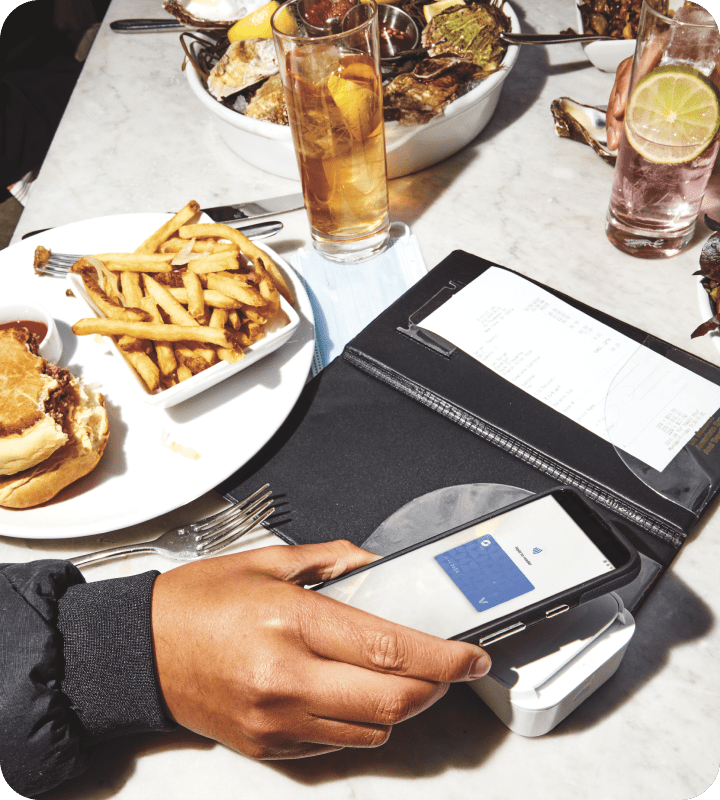 Half-eaten hamburger and chips next to a bill at a restaurant