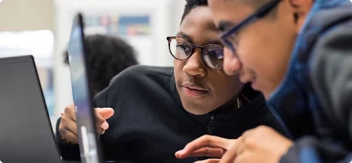 Two students with laptops in front of them