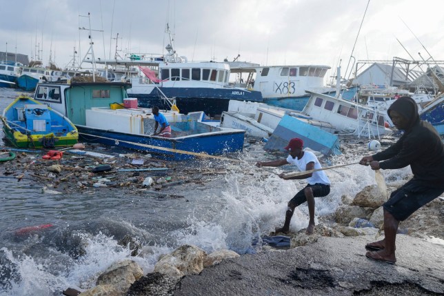 A picture of fishermen pull a boat damaged by Hurricane Beryl back to the dock at the Bridgetown Fisheries in Barbados