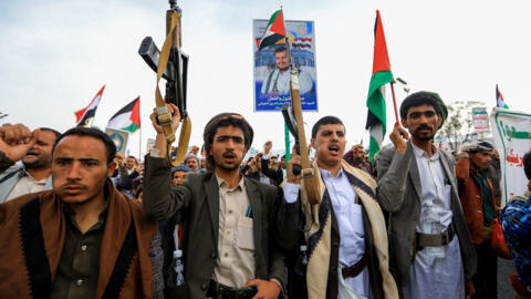 Protesters lift placards, flags of Yemen and Palestine, and rifles during a rally in the Huthi-controlled capital Sanaa in solidarity with Palestinians on July 19, 2024.