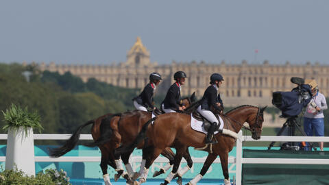 Great Britain's gold medallists Rosalind Canter, Laura Collett and Tom McEwen take a victory tour in front of the Palace of Versailles outside Paris on July 29, 2024.