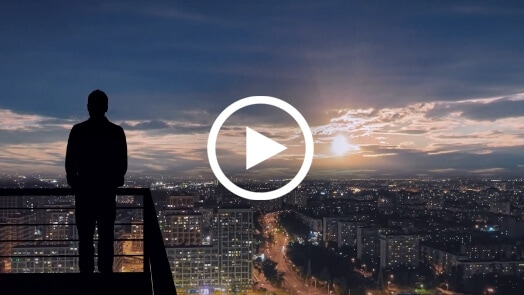 Person on balcony, overlooking an urban landscape at sunrise or sunset